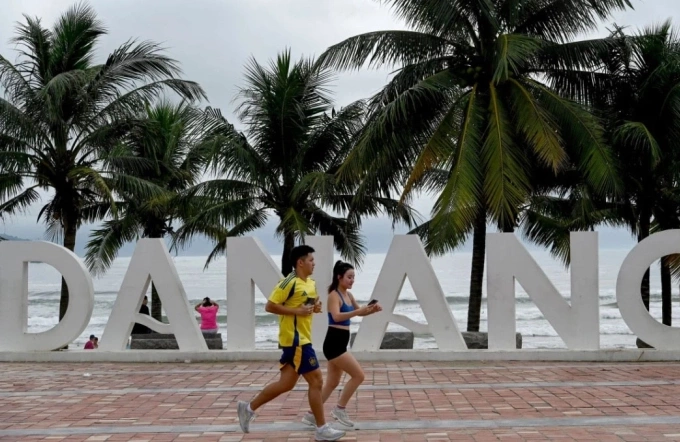 Hai du kh&aacute;ch đang chạy bộ trước một b&atilde;i biển ở Đ&agrave; Nẵng. Ảnh: AFP