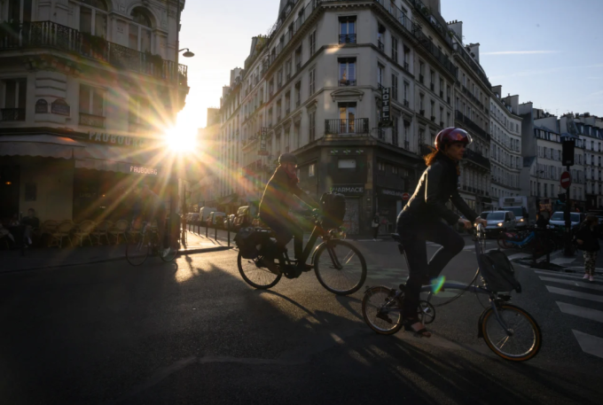 Người d&acirc;n đạp xe đi l&agrave;m qua giao lộ ở Paris. Ảnh: AFP